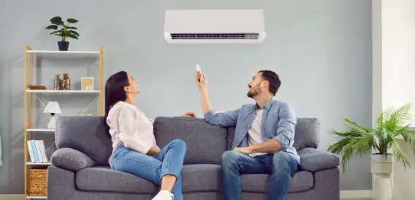 Pareja disfrutando del confort de su hogar con un aire acondicionado que ofrece un boost de aire fresco.